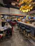 Churchill Bar and Lounge (Dover Marina Hotel): Bar counter with five high stools, marble floor, several round tables with red chairs, and two staff members behind the bar area.